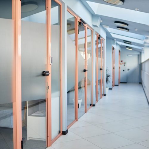 Background shot of transparent glass doors decorated with privacy decals leading to individual office spaces in contemporary business center, copy space