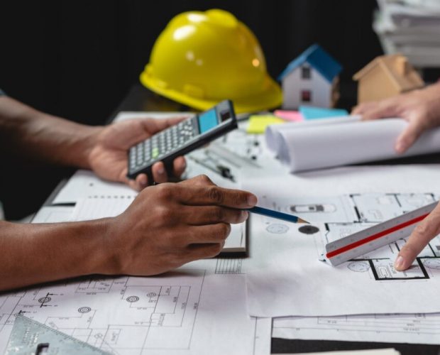 Team of engineers reviewing blueprints Sketch of a new construct Team of engineers reviewing blueprints Sketch of a new construction project with engineering tools at office desk. For improvement of house designs in mortgage, rent, sale, real estate